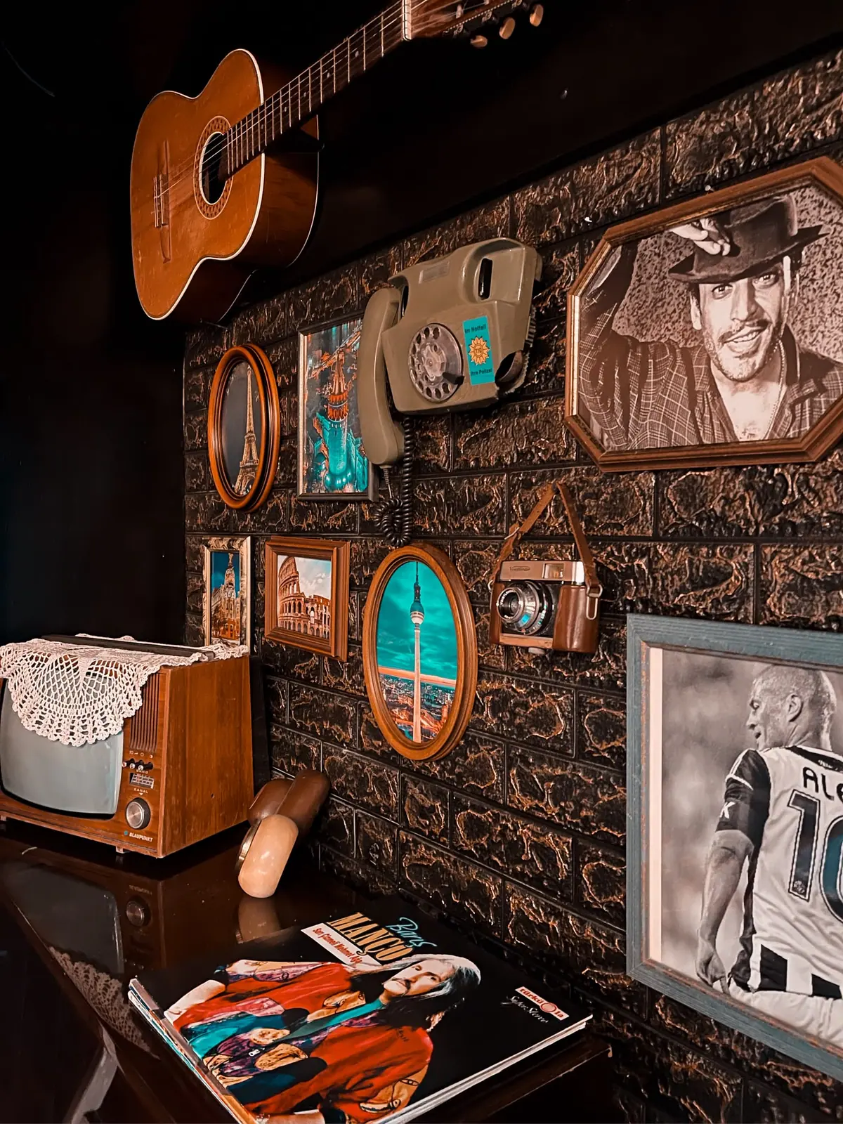 Vintage-Ecke mit Akustikgitarre an der Wand, altem Wählscheibentelefon und Röhrenfernseher