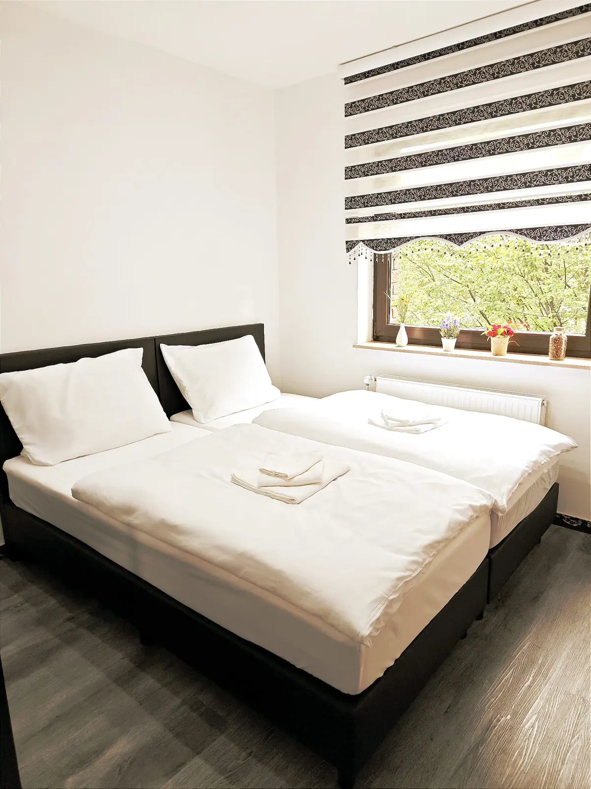 Zweibettzimmer im Tageslicht mit weißer Bettwäsche und Vinylboden in Holzoptik